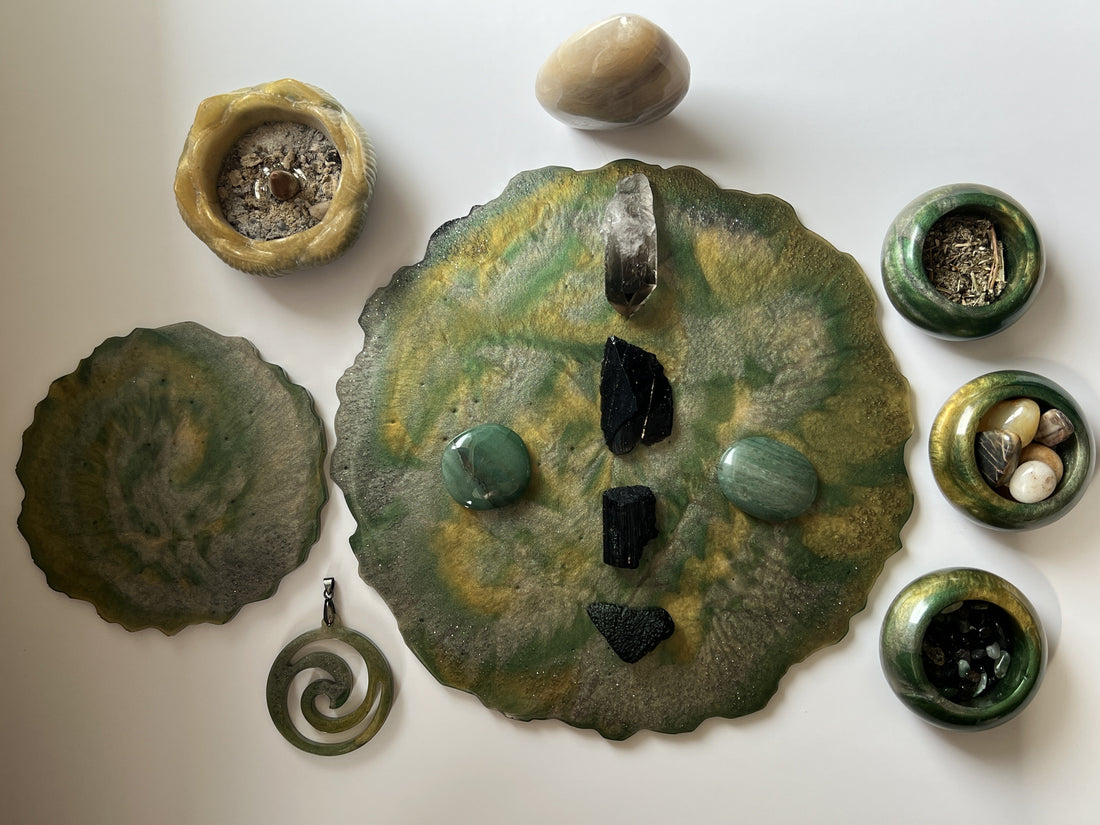 Handmade green and gold resin catch-all tray with Capricorn ritual crystals including black tourmaline, smoky quartz, and green aventurine, surrounded by resin tiny bowls filled with herbs and stones, spiral pendant, and incense holder on white background