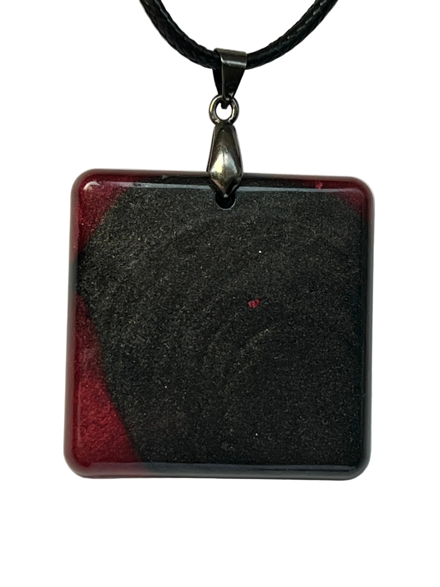 Handcrafted rounded square resin pendant with black holographic shimmer dominating the center and bold crimson red accents at the corners, suspended from a silver chain with a silver-toned bail.