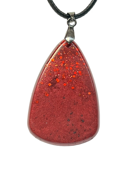Handcrafted wide teardrop resin pendant with deep crimson base and cascading red glitter concentrated at the apex, suspended from a black braided cord with a silver-toned bail.