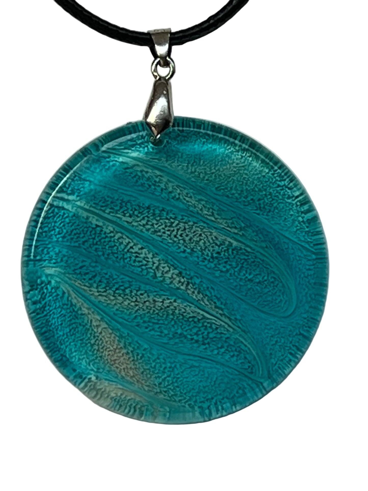 Handcrafted circle resin pendant with vivid ocean teal and sweeping silver-white current details throughout deep shimmer texture, suspended from a black braided cord with a silver-toned bail.