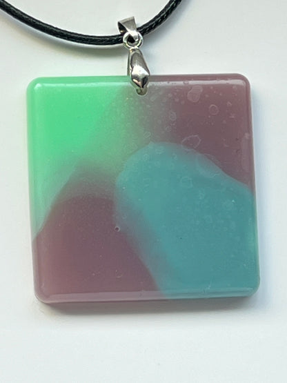 Handcrafted square resin pendant with soft swirling mint green, dusty rose, and ocean blue opaque pigments, suspended from a silver chain with a silver-toned bail.