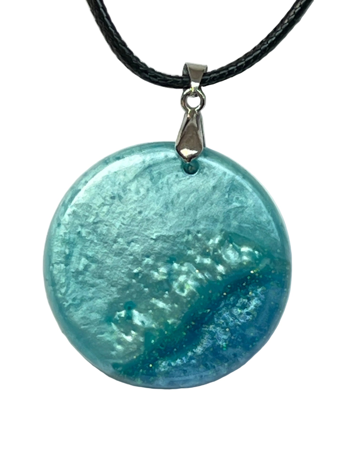 Handcrafted circle resin pendant with pearl aqua, teal, and deep cobalt blue organic foam texture with gold and green glitter flecks, suspended from a silver chain with a silver-toned bail.