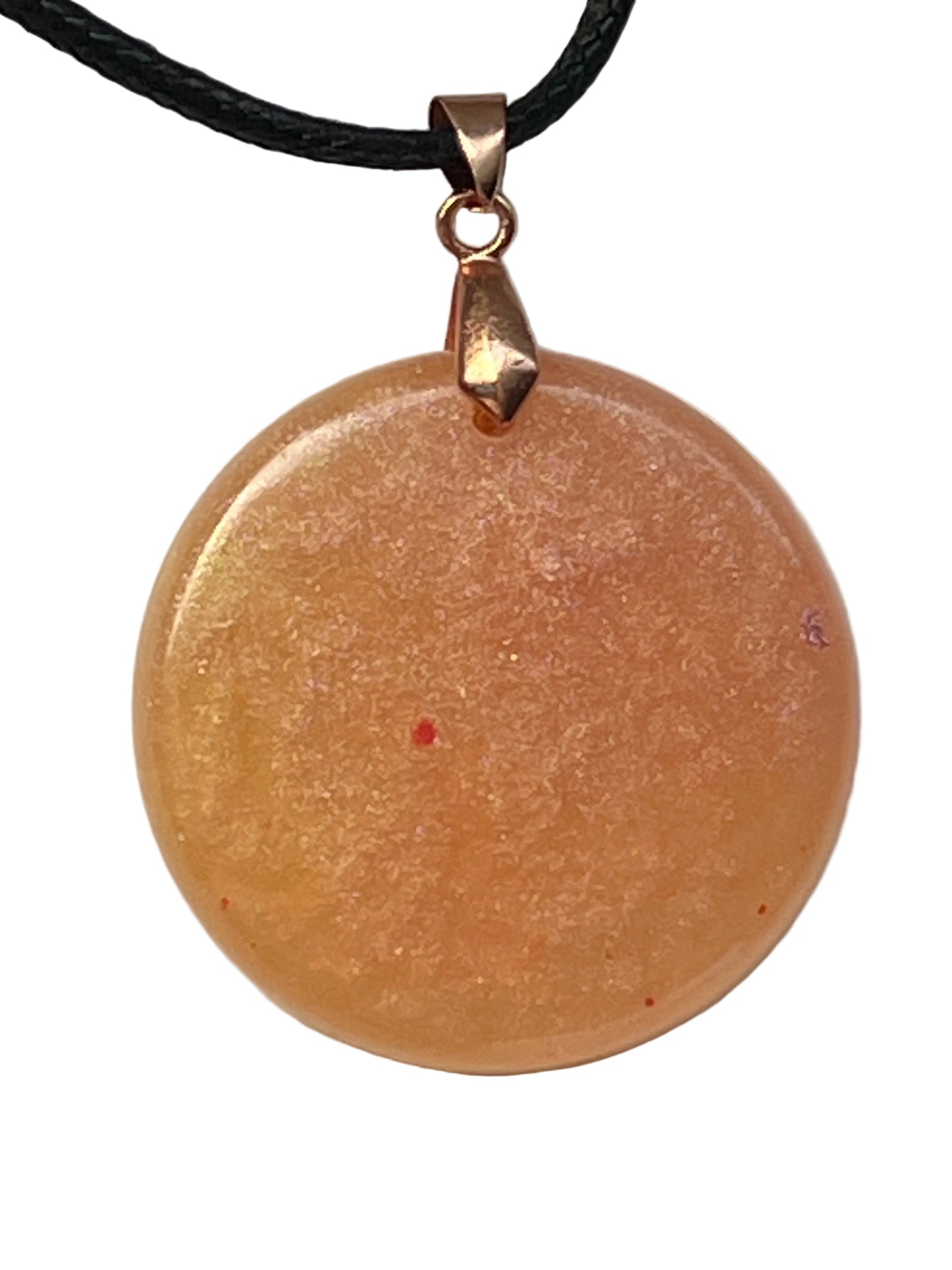 Handcrafted golden amber circle resin pendant with rose shimmer and scattered crimson flecks, suspended from a black braided cord with a copper-toned bail.