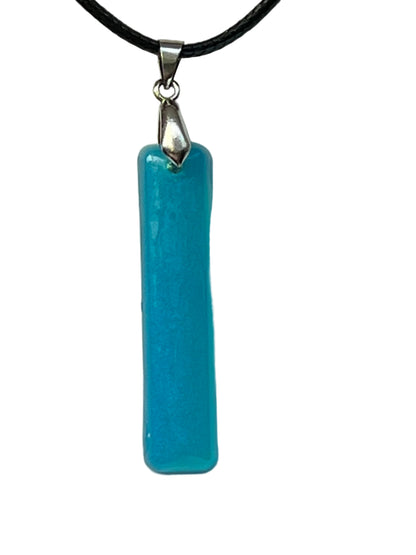 Handcrafted turquoise bar resin pendant with vivid pearlescent shimmer, suspended from a black braided cord with a silver-toned bail.