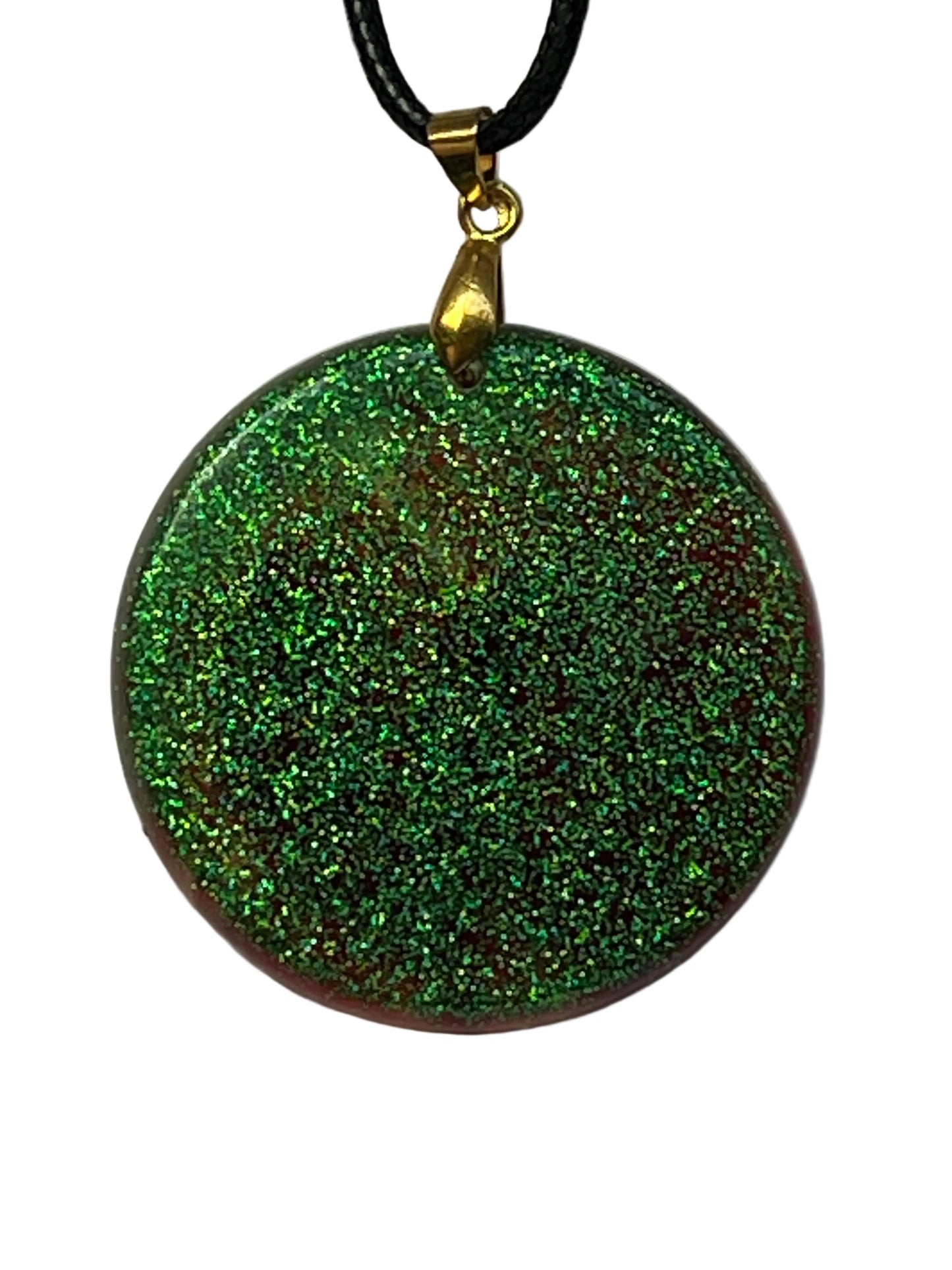 Handcrafted resin large circle pendant with dense holographic green glitter over a deep burgundy base creating rich multidimensional sparkle, suspended from a black braided cord with a gold-toned bail.