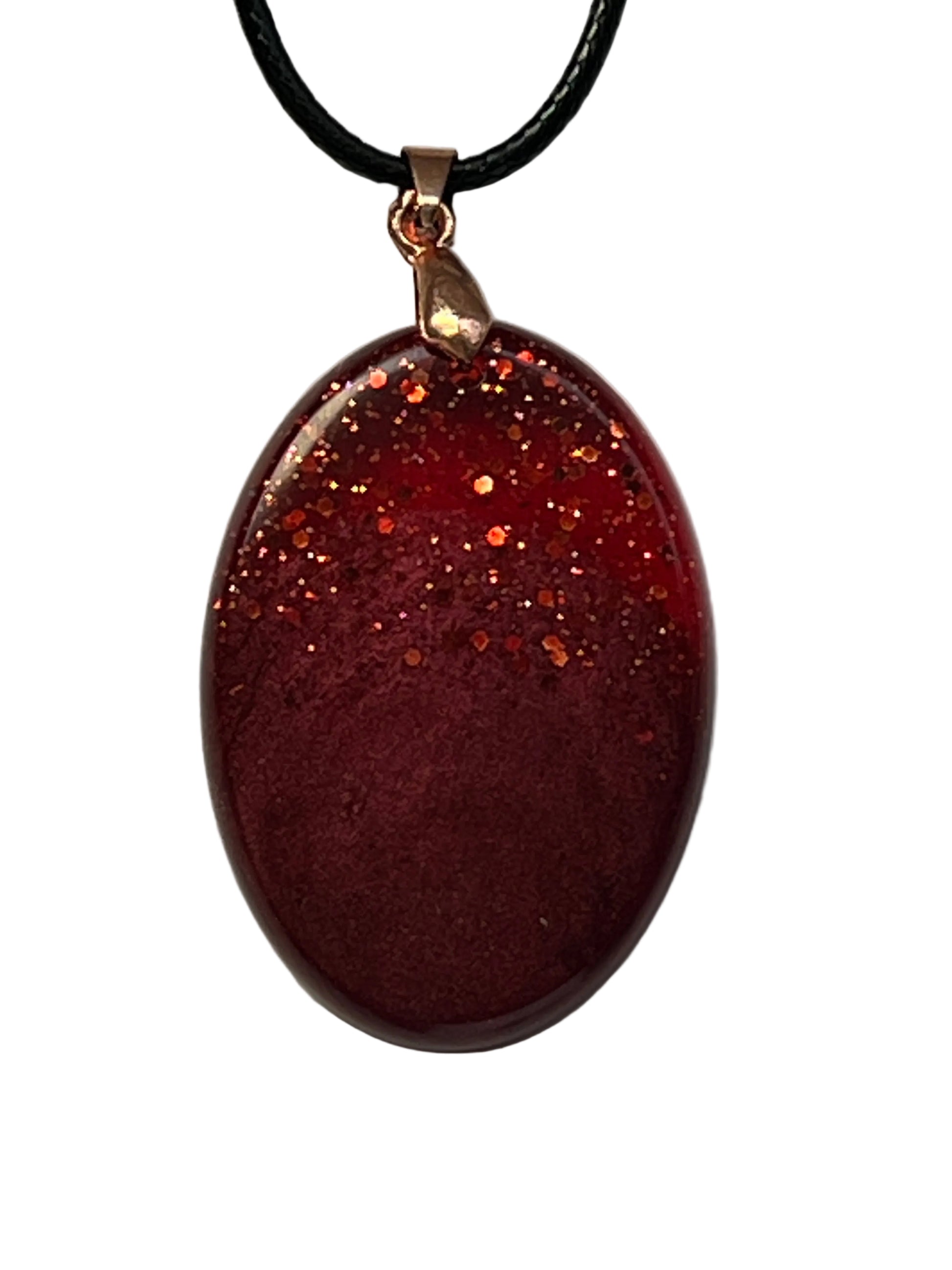 Handcrafted deep burgundy red resin oval pendant with scattered copper and orange glitter in the upper portion fading into a rich velvety matte base, suspended from a black braided cord with a copper-toned bail.