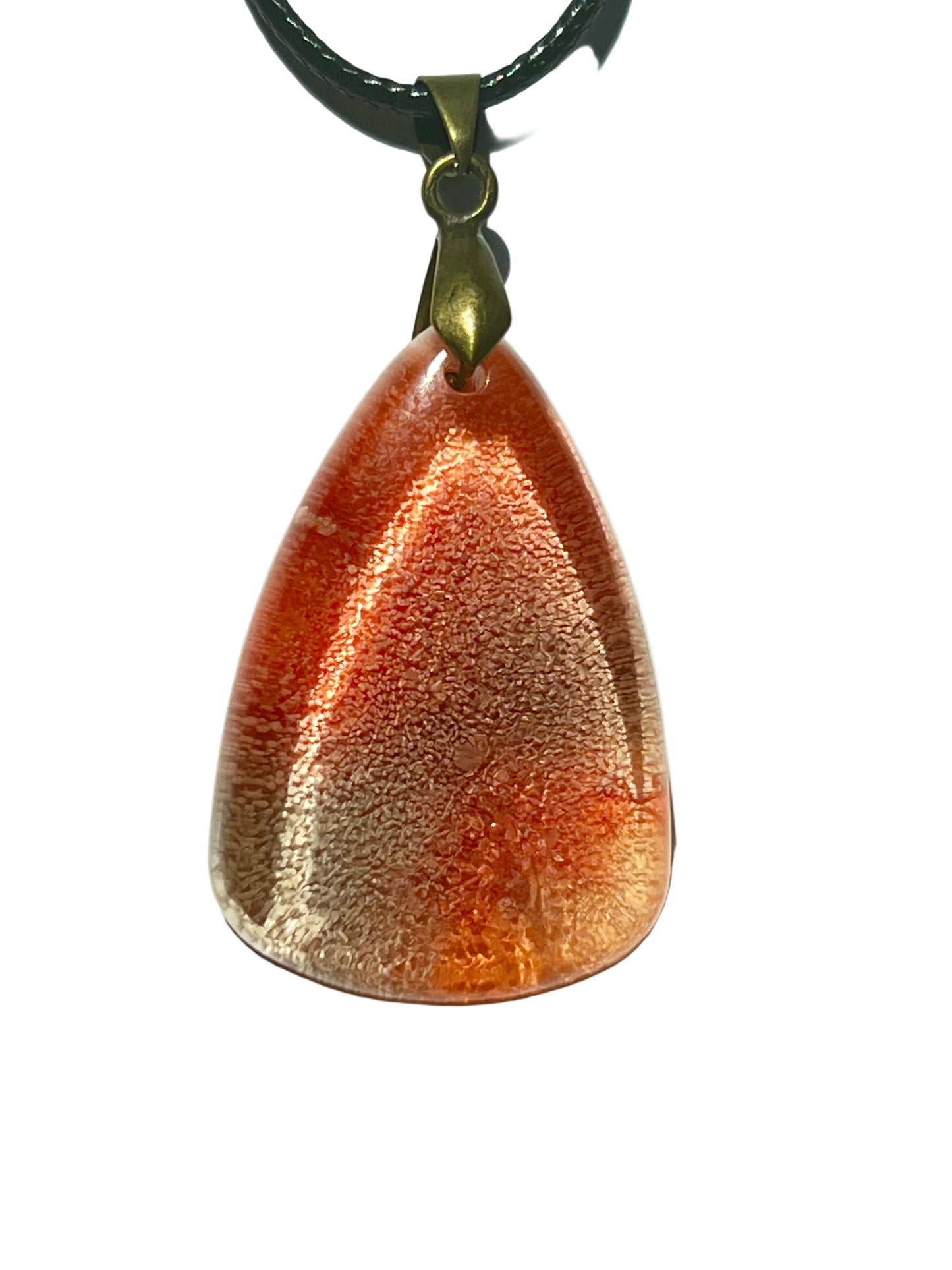 Handcrafted warm translucent peach and burnt orange resin wide teardrop pendant with a blazing copper shimmer center fading to luminous champagne edges and fine copper and gold shimmer throughout, suspended from a black braided cord with an antique bronze bail.
