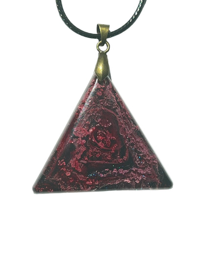 Handcrafted resin triangle pendant with deep black base featuring a swirling crimson and magenta rose pattern with scattered hot pink glitter and a deep blue iridescent accent along the base, suspended from a black braided cord with an antique bronze bail.
