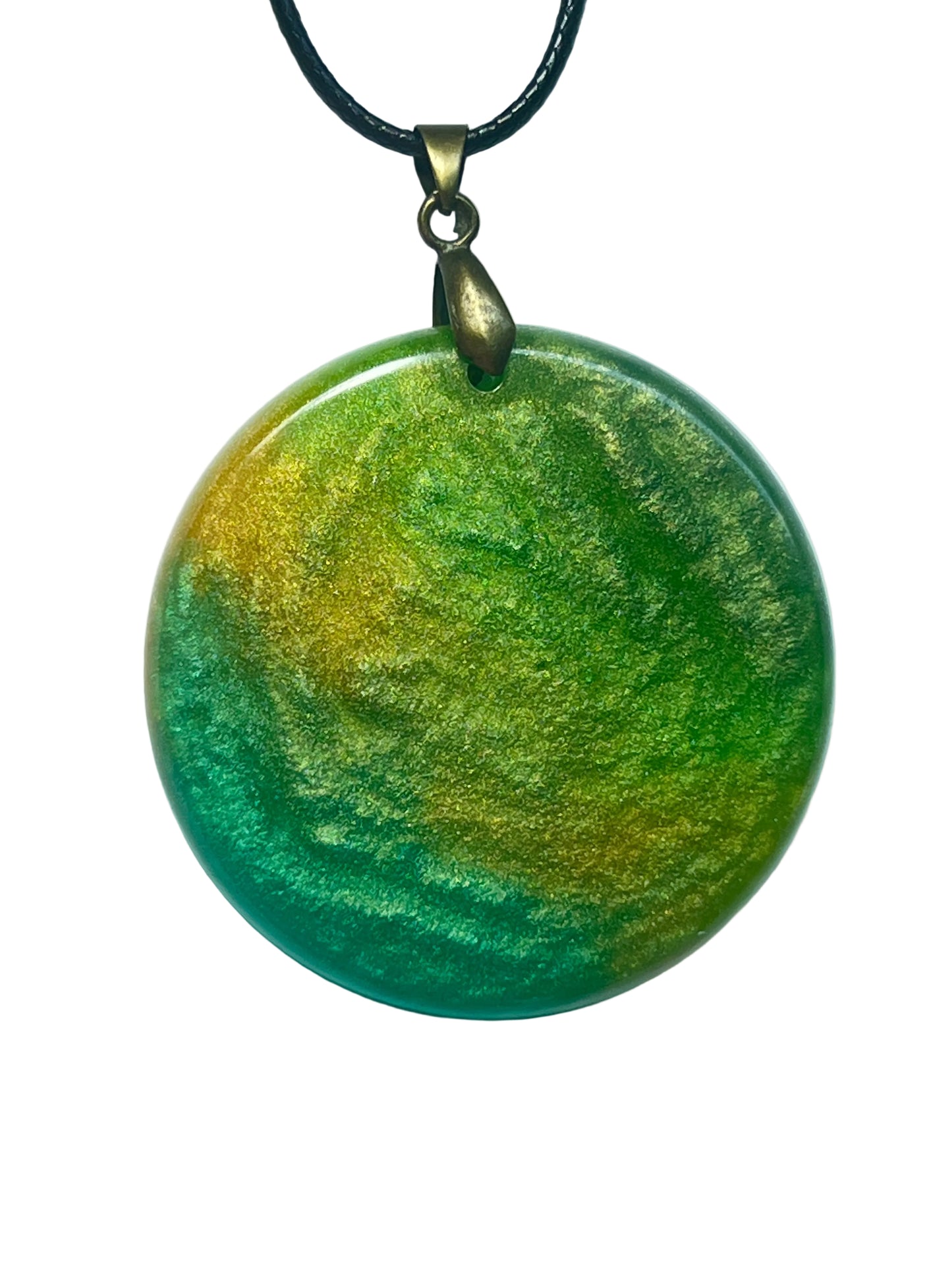 Handcrafted resin large domed circle pendant with swirling forest green, emerald, and chartreuse tones and a sweeping warm gold shimmer band, with deep teal green edges and atmospheric surface texture, suspended from a black braided cord with an antique bronze bail.