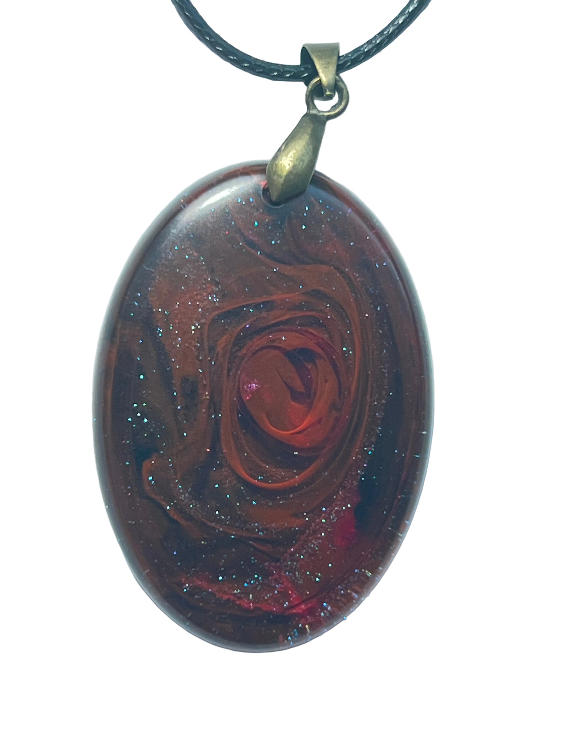 Handcrafted resin domed oval pendant with deep burgundy and dark brown base featuring a swirling burnt orange rose-like spiral at center and iridescent blue and silver glitter throughout, suspended from a black braided cord with an antique bronze bail.