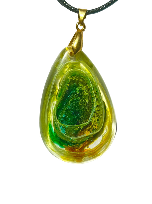 Handcrafted resin teardrop pendant with translucent golden yellow outer layer revealing a layered green geode-like interior cavity with emerald and teal glitter crystal center, suspended from a black braided cord with a gold-toned bail.