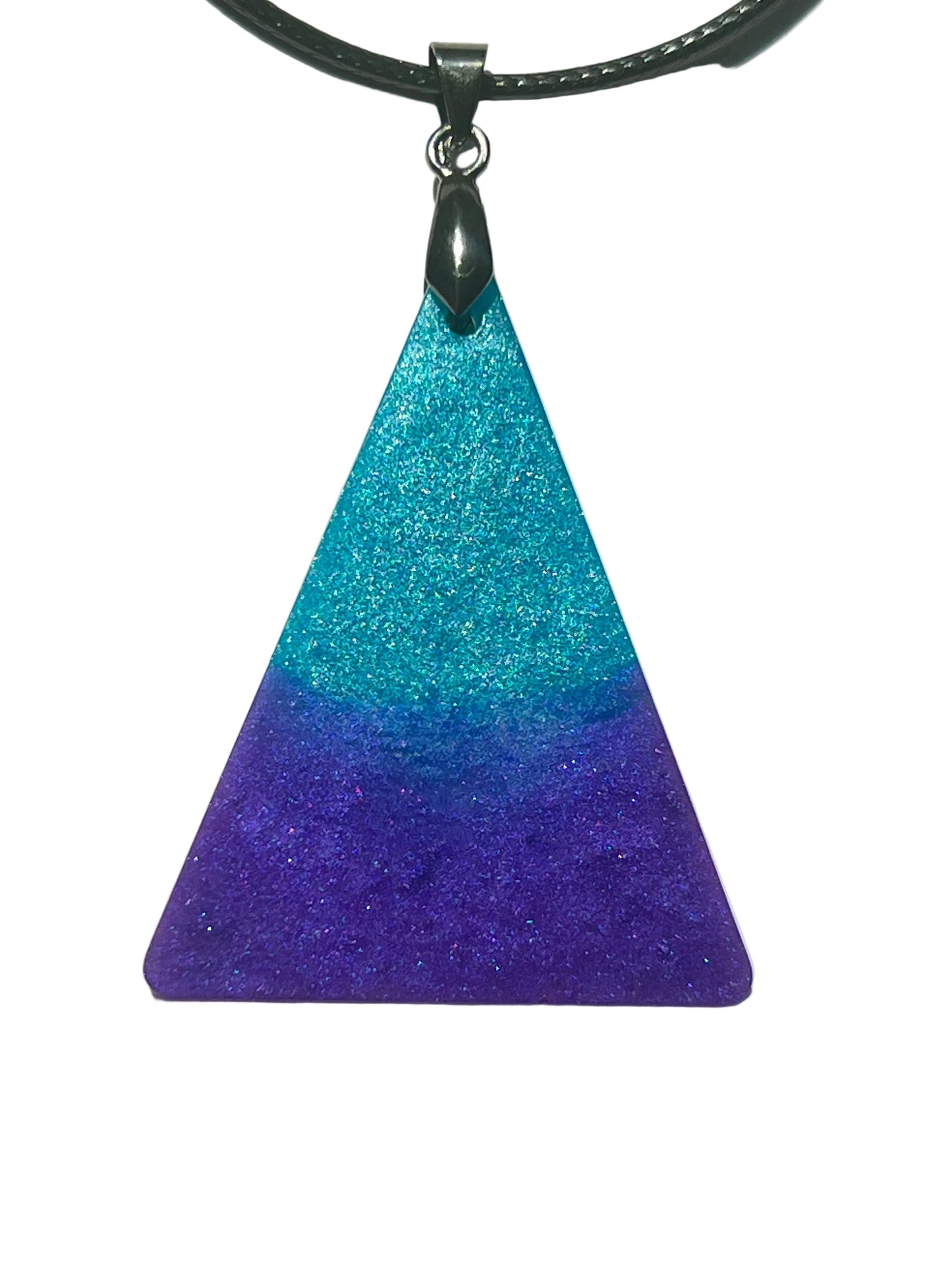 Handcrafted resin triangle pendant with electric turquoise and teal shimmer at the apex fading into rich deep violet at the base with fine iridescent glitter throughout, suspended from a black braided cord with a gunmetal bail.