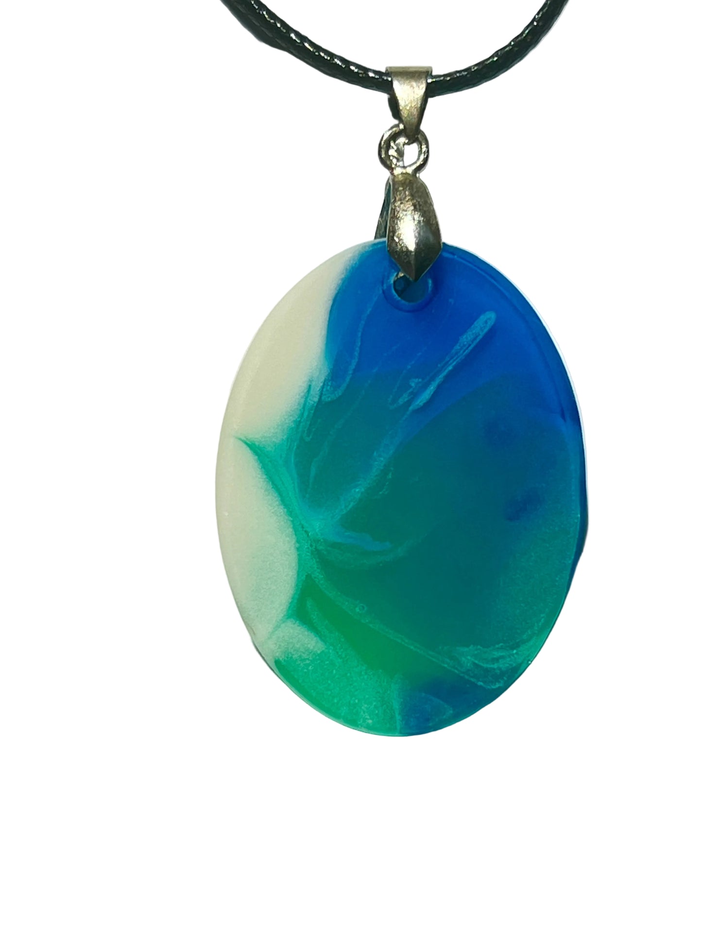 Handcrafted resin oval pendant with deep cobalt blue, vivid teal and emerald green swirls, and creamy pearl white in a dynamic coastal wave pattern, suspended from a black braided cord with a silver-toned bail.