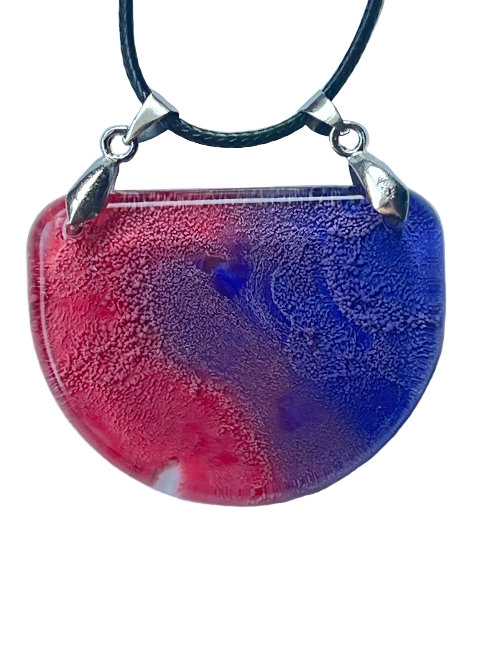 Handcrafted resin half moon pendant with warm rose and crimson on the left sweeping into deep cobalt and royal blue on the right with a blue-violet vortex at center and fine cellular texture throughout, suspended from a black braided cord with dual silver-toned bails.