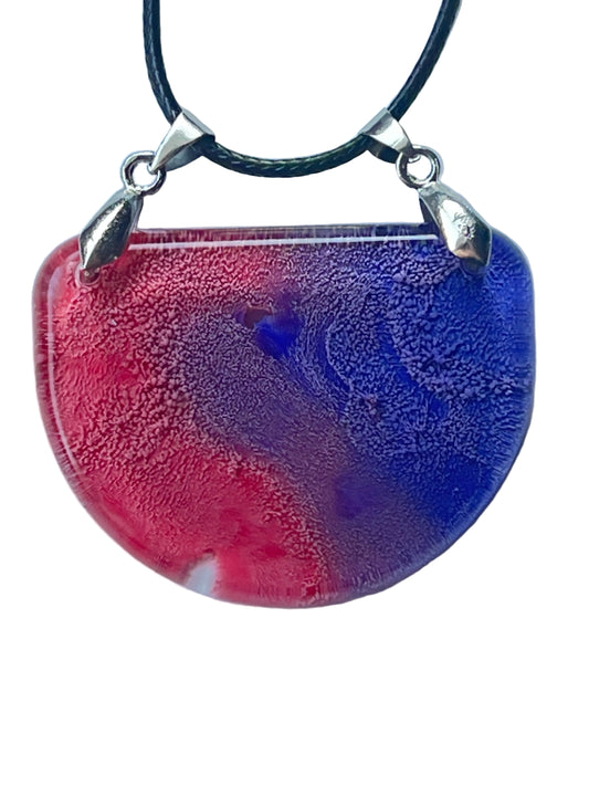 Handcrafted resin half moon pendant with warm rose and crimson on the left sweeping into deep cobalt and royal blue on the right with a blue-violet vortex at center and fine cellular texture throughout, suspended from a black braided cord with dual silver-toned bails.