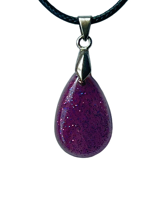 Handcrafted deep magenta-purple resin smooth domed teardrop pendant with dense iridescent glitter in lavender, pink, and blue creating an atmospheric jewel-toned effect, suspended from a black braided cord with a silver-toned bail.
