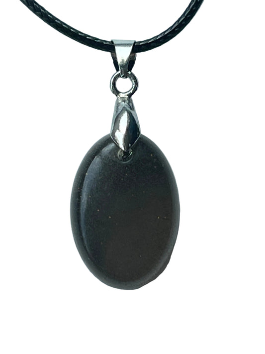 Handcrafted deep matte charcoal grey resin oval pendant with fine texture and subtle micro-sparkle giving a polished dark stone-like quality, suspended from a black braided cord with a silver-toned bail.

Next one whenever you're ready! 🌙✨