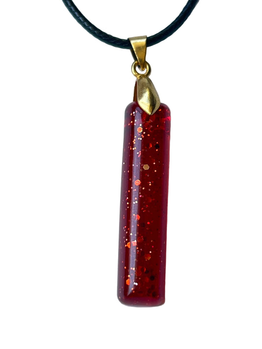 Handcrafted deep translucent crimson resin tall rectangular bar pendant with suspended red and copper hexagonal glitter in mixed sizes creating a fiery inner glow, suspended from a black braided cord with a gold-toned flame leaf bail.