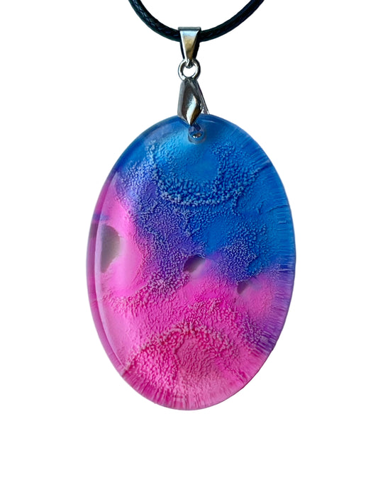 Handcrafted resin large oval pendant with vivid translucent hot pink lower field and sweeping blue-violet cellular texture fading to rich periwinkle upper tones with natural clear window formations throughout, suspended from a black braided cord with a silver-toned bail.