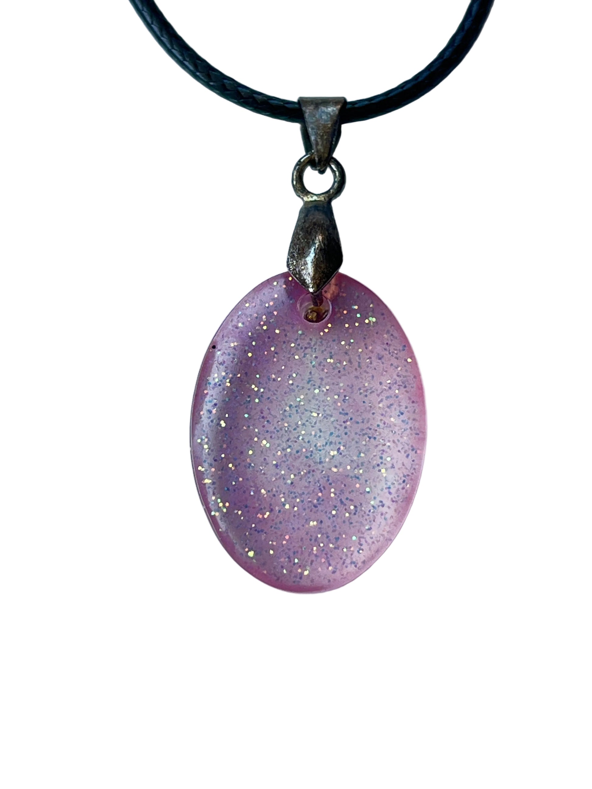 Handcrafted soft translucent rose pink resin oval pendant with dense fine iridescent glitter in gold, silver, lavender, and blue creating a glowing starlight effect, suspended from a black braided cord with a gunmetal bail.
