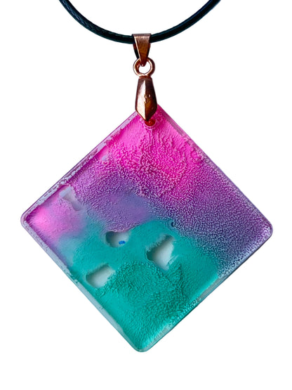 Handcrafted resin diamond-shaped pendant with warm pink and magenta upper field fading through lavender into fresh mint and seafoam green with fine cellular texture and natural clear organic window formations throughout, suspended from a black braided cord with a copper-toned bail.
