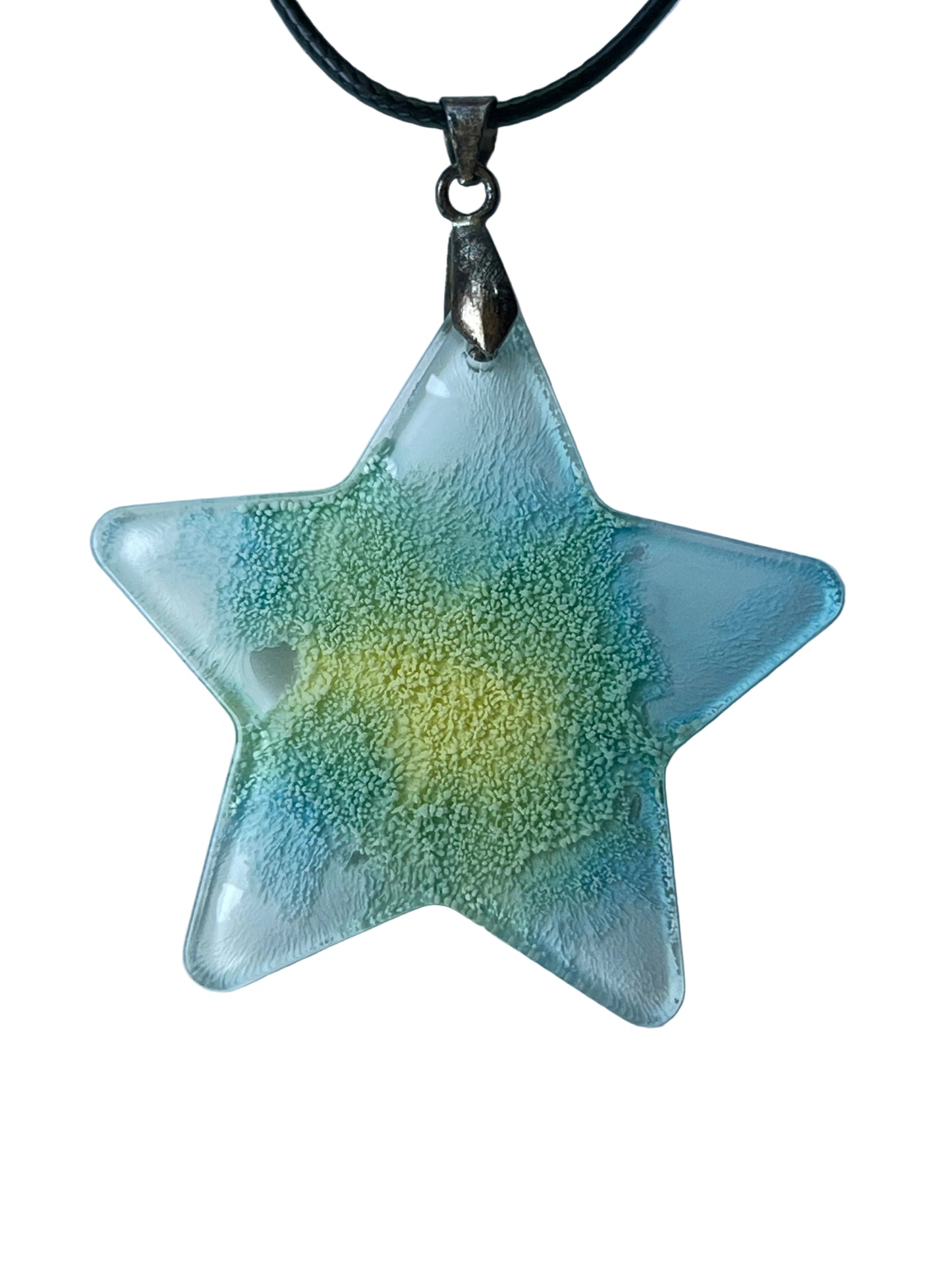 Handcrafted resin star pendant with a warm yellow glowing center radiating through chartreuse and soft green into aqua and seafoam teal with fine cellular texture and crystal clear transparent edges at the star points, suspended from a black braided cord with an antique bronze bail.