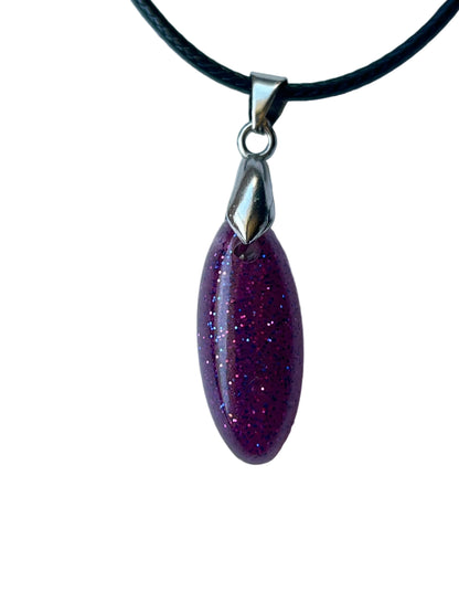 Handcrafted deep opaque plum and berry purple resin elongated marquise pendant densely filled with fine iridescent glitter shifting between magenta-pink and electric blue, suspended from a black braided cord with a silver leaf bail.