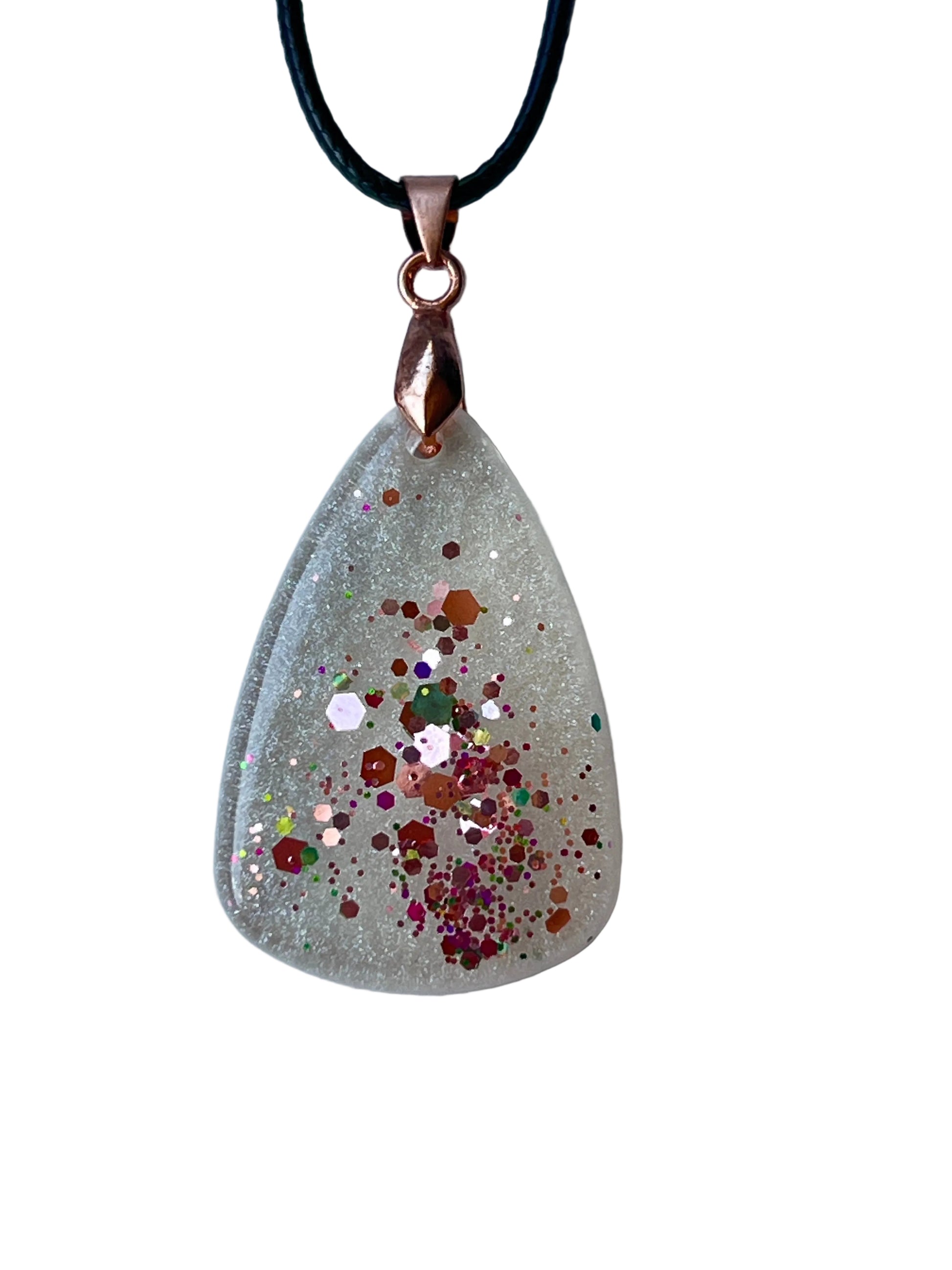 Handcrafted crystal clear and frosted white resin wide teardrop pendant with a central cluster of rose gold and copper hexagon confetti surrounded by scattered magenta, burgundy, and iridescent fine glitter, suspended from a black braided cord with a copper-toned bail.