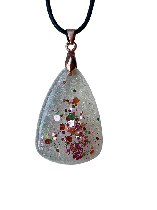 Handcrafted crystal clear and frosted white resin wide teardrop pendant with a central cluster of rose gold and copper hexagon confetti surrounded by scattered magenta, burgundy, and iridescent fine glitter, suspended from a black braided cord with a copper-toned bail.