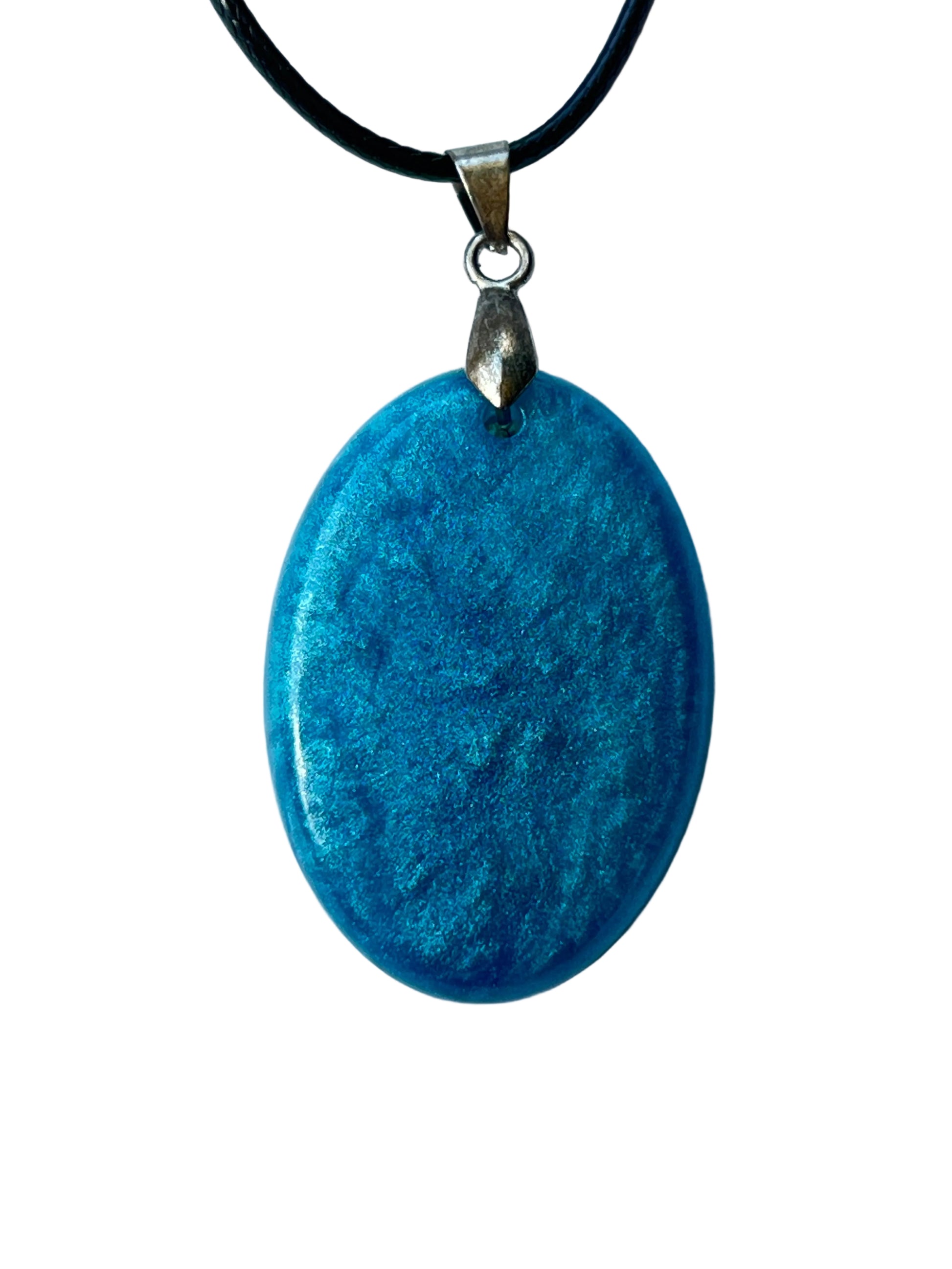 Handcrafted rich matte teal resin large oval pendant with fine organic texture and subtle tone variation throughout giving a deep polished stone-like quality, suspended from a black braided cord with a silver-toned bail.