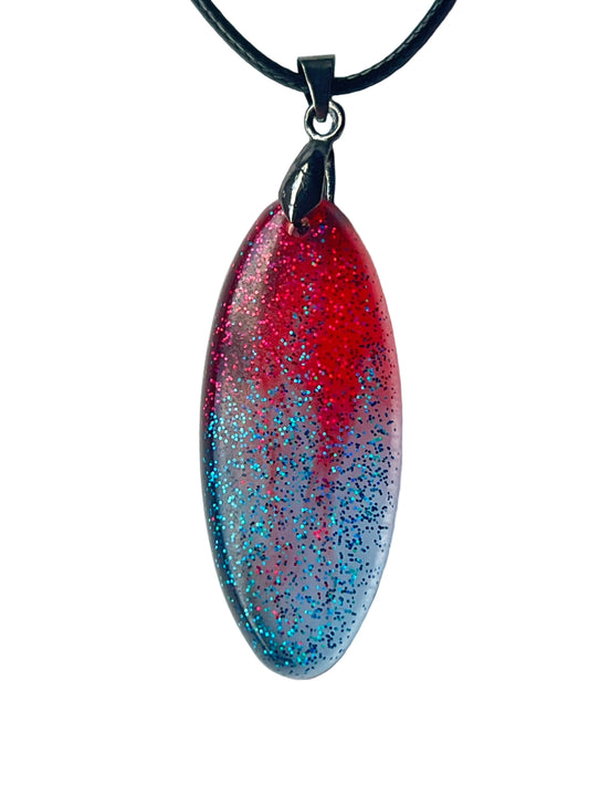 Handcrafted resin elongated marquise pendant with vivid translucent crimson upper field densely filled with magenta-red and pink glitter fading through mauve-purple into cool silver-lavender lower field with dense electric teal and blue glitter, suspended from a black braided cord with a gunmetal bail.