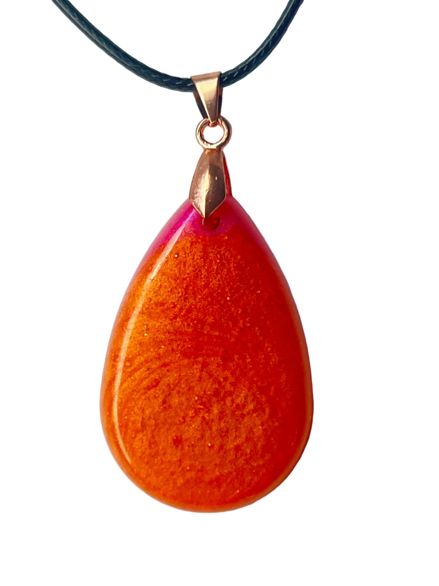 Handcrafted large resin teardrop pendant with deep metallic copper-orange body featuring swirling fine gold shimmer throughout and a vivid translucent hot magenta and fuchsia crown at the apex, suspended from a black braided cord with a rose gold bail.