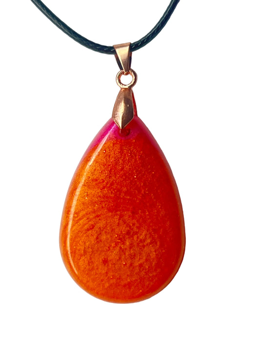 Handcrafted large resin teardrop pendant with deep metallic copper-orange body featuring swirling fine gold shimmer throughout and a vivid translucent hot magenta and fuchsia crown at the apex, suspended from a black braided cord with a rose gold bail.
