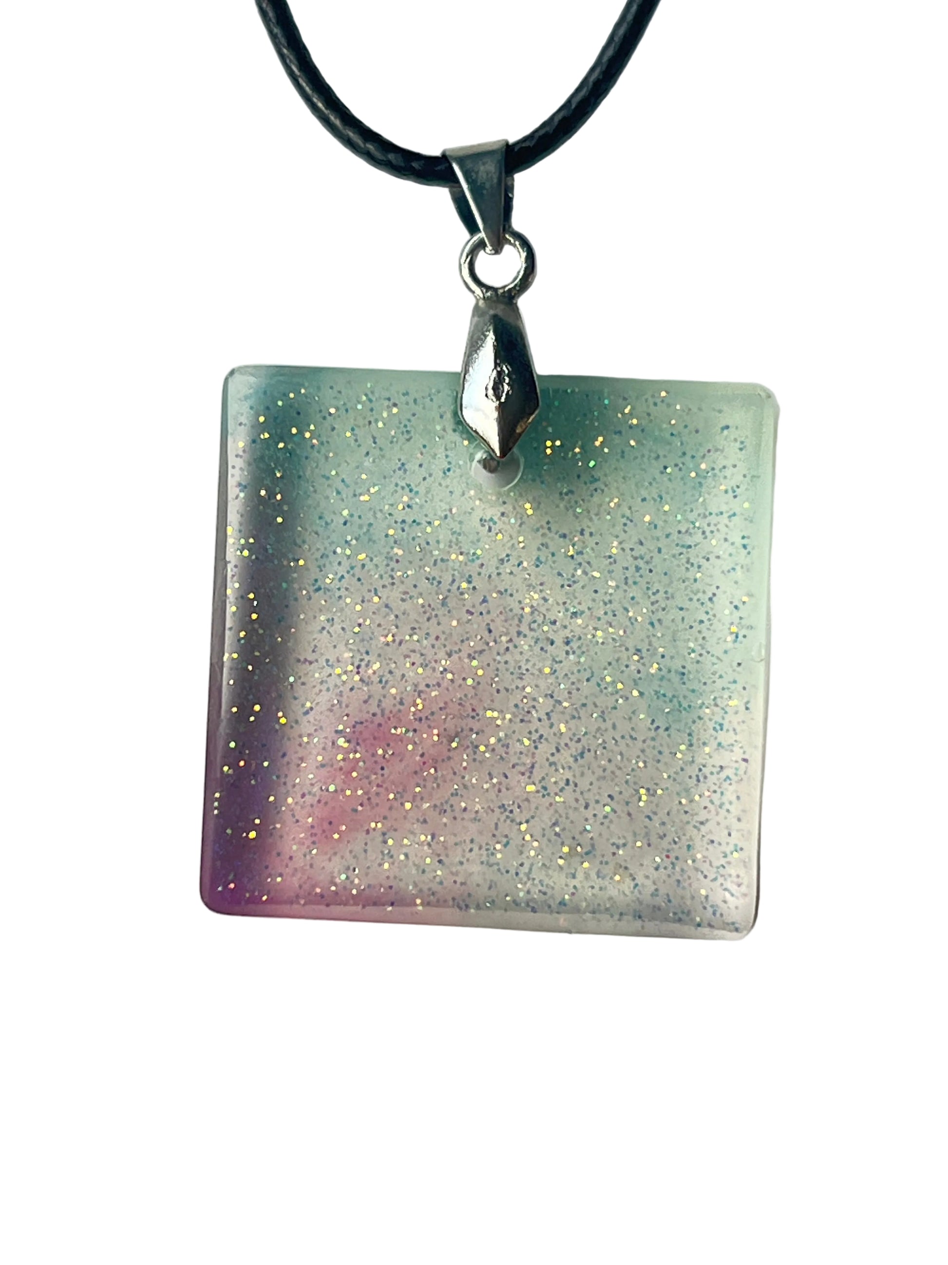 Handcrafted clear translucent resin square pendant worn on point with soft mint green and blush mauve color washes and extraordinarily fine iridescent glitter throughout shifting between silver, gold, lavender, and pale aqua, suspended from a black braided cord with a silver-toned bail.