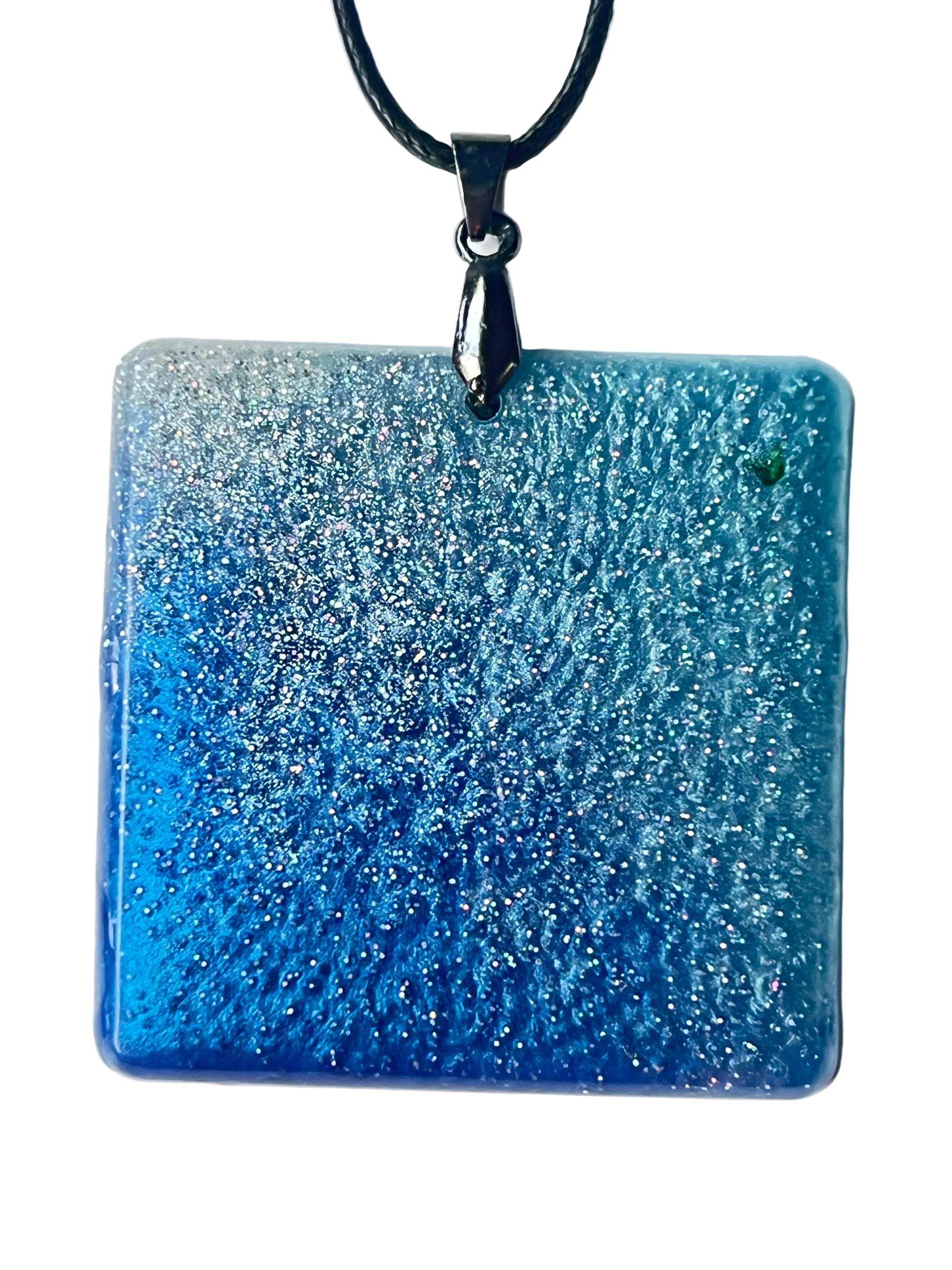 Handcrafted large resin square pendant in rich saturated cobalt and royal blue with intricate cellular texture and extraordinarily dense ultra-fine iridescent silver glitter throughout fading to silvery periwinkle in the upper field, suspended from a black braided cord with a gunmetal bail.