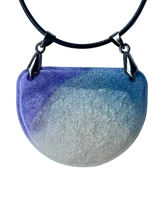 Handcrafted wide fan-shaped resin bib pendant with rich violet and periwinkle-blue upper left field fading into luminous silver-white lower field with extraordinarily fine silver mica shimmer and subtle lace-like surface texture throughout, suspended from a black braided cord via two gunmetal bails at the upper corners.