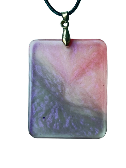 Handcrafted large resin rounded rectangle pendant with soft translucent blush and dusty rose upper right field meeting a complex swirling lavender-grey in a dramatic diagonal sweep with watercolor-like atmospheric blending throughout, suspended from a black braided cord with an antiqued brass bail.