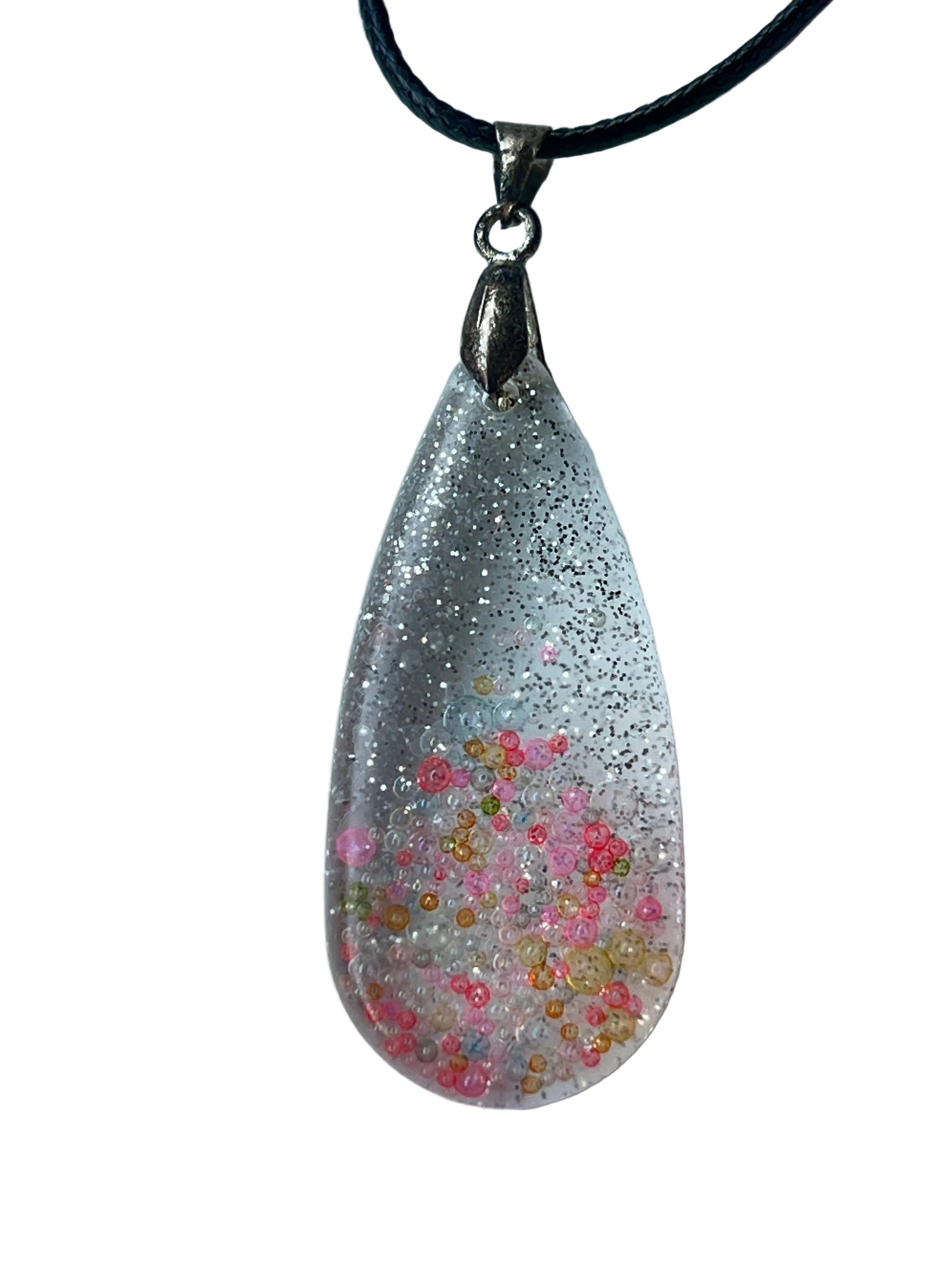 Handcrafted clear crystal resin tall teardrop pendant with dense ultra-fine silver glitter in the upper field and scattered multicolor micro-bubbles in soft pink, coral, amber, and pale green throughout the lower field at varying depths, suspended from a black braided cord with a silver-toned bail.