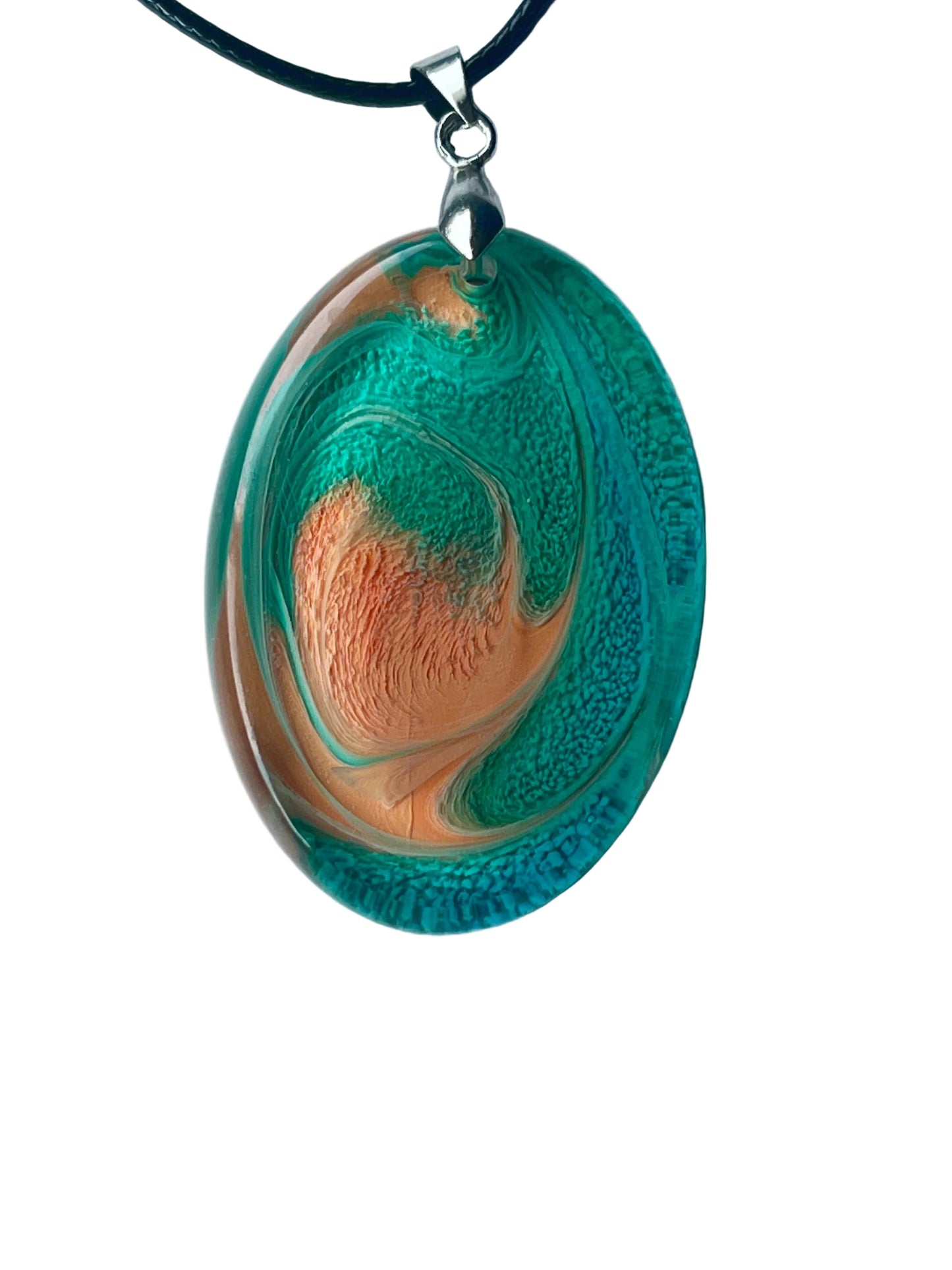 Handcrafted large resin oval pendant with vivid saturated teal outer ring and swirling upper band with intricate cellular texture surrounding a warm peach and coral-salmon center with fine radiating texture, suspended from a black braided cord with a silver-toned bail.