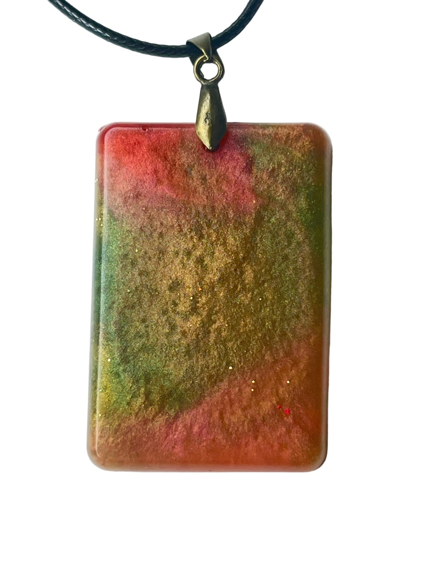 Handcrafted large resin rounded rectangle pendant with warm coral-red and dusty rose clouds meeting rich olive and khaki-gold formations in a painterly atmospheric blend throughout with fine complex texture, suspended from a black braided cord with an antiqued brass bail.