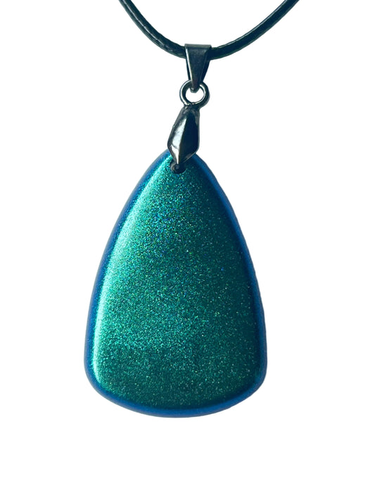 Handcrafted resin teardrop pendant with extraordinarily dense ultra-fine chrome metallic shimmer shifting between vivid emerald-teal and electric sapphire-blue throughout with a deep cobalt-blue edge visible along all sides, suspended from a black braided cord with a gunmetal bail.