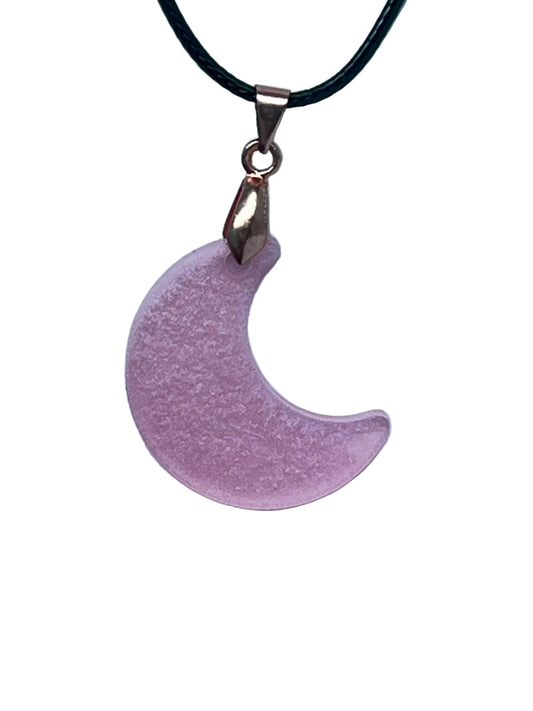 Handcrafted frosted mauve resin crescent moon pendant with fine pearly shimmer, suspended from a black braided cord with a rose gold bail.