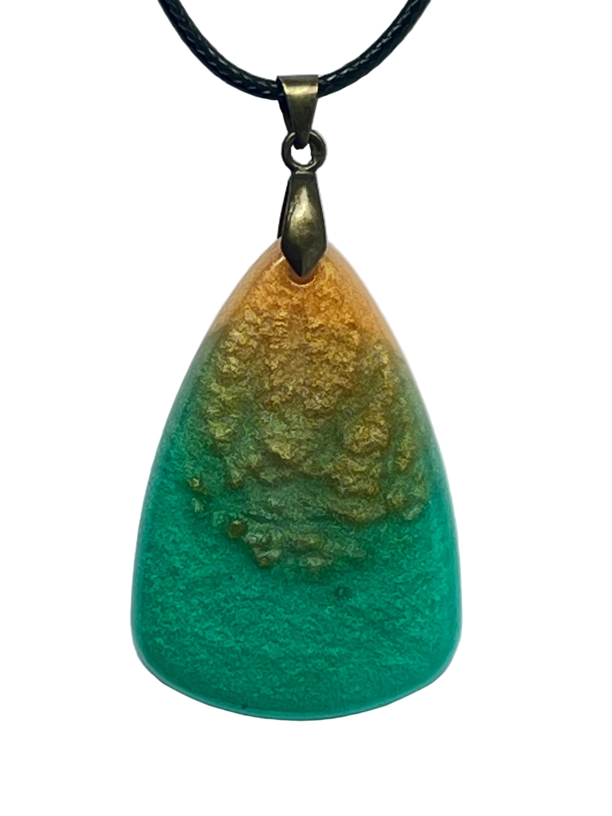 Handcrafted resin generous teardrop pendant with warm pearlescent amber and burnt gold upper portion transitioning through an organic mixed zone to a rich teal-green base, suspended from a black braided cord with an antiqued brass bail.