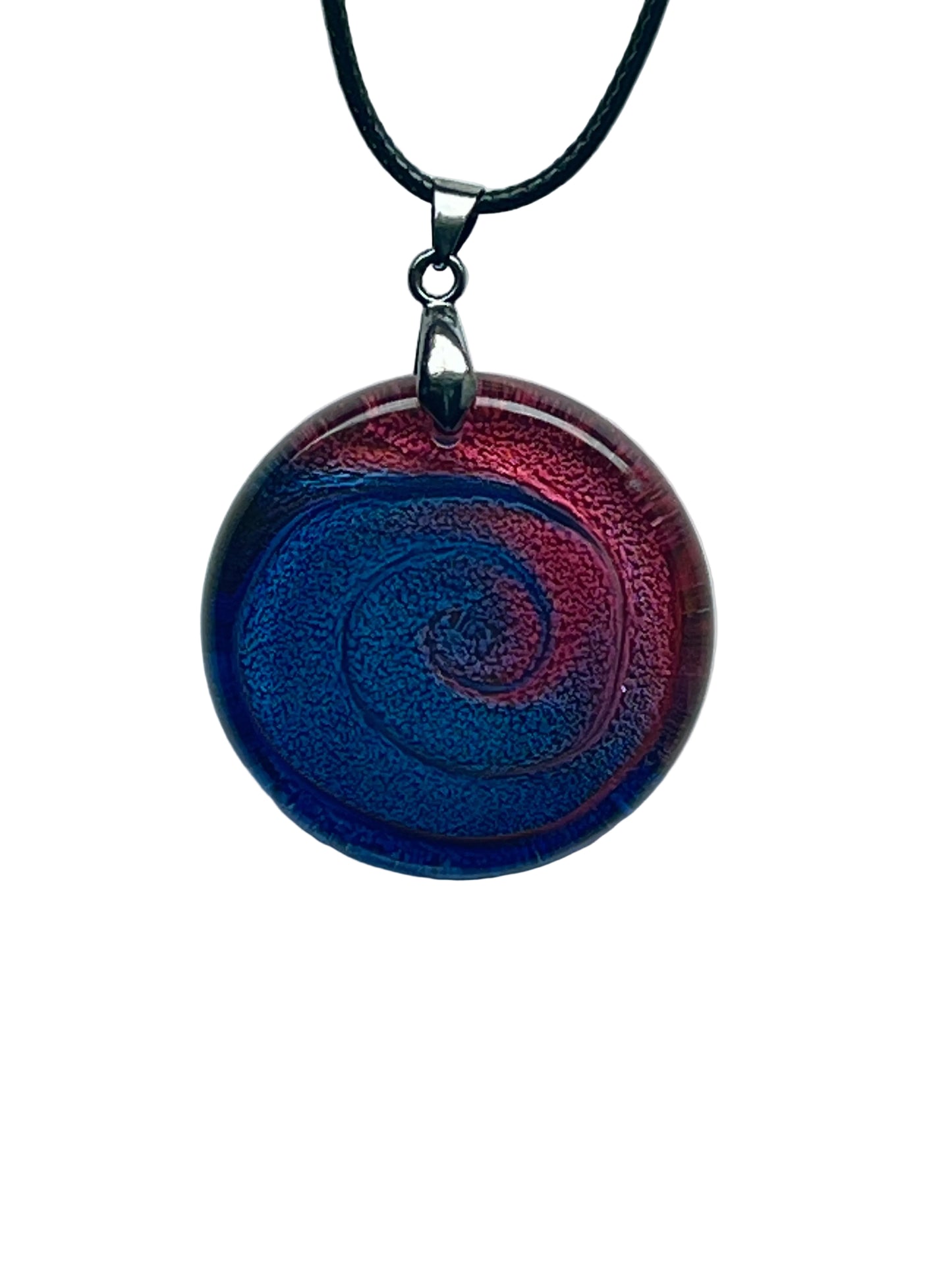 Handcrafted resin large circle pendant with a saturated crimson red outer rim sweeping inward in a dramatic spiral to a deep cobalt and sapphire blue center, with rich textured shimmer throughout, suspended from a black braided cord with a silver-toned bail.