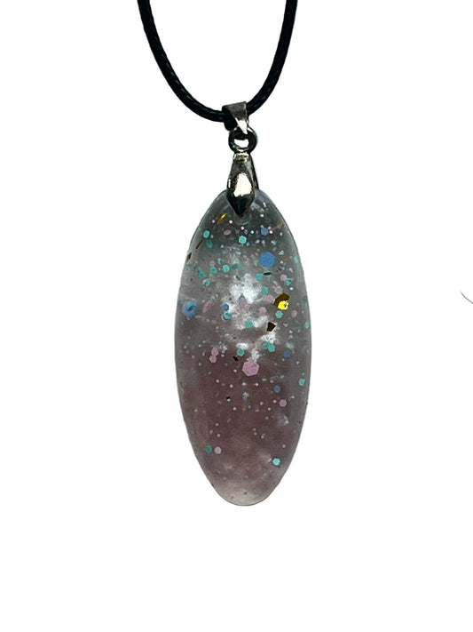 An elongated marquise-shaped resin pendant with a translucent dusty mauve base, scattered throughout with turquoise, blue, pink, and gold confetti flecks and soft white cloud-like swirls. It hangs from a silver-toned bail on a black braided cord against a pale background.