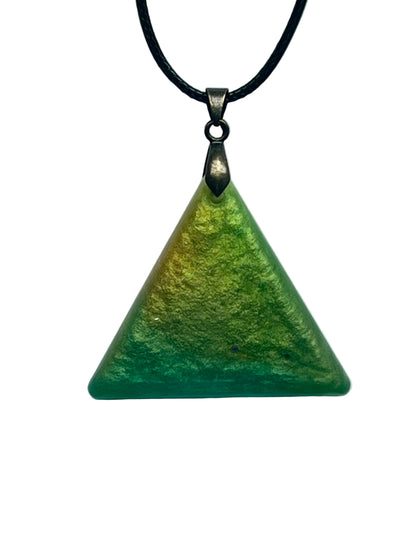 A triangular resin pendant with a gradient from golden chartreuse and shimmering gold at the top peak to deep forest and jade green at the base, with a soft mottled texture. It hangs from an antiqued brass bail on a black braided cord against a pale background.