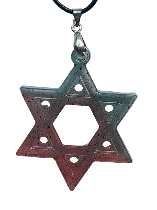 A six-pointed star (hexagram) resin pendant with a gradient from teal and slate at the top points to coral and red at the bottom, scattered with fine black speckles, a single dot on each point, and an open hexagonal center. It hangs from a silver-toned bail on a black braided cord against a pale background.