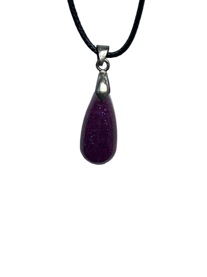 A small, elongated teardrop-shaped resin pendant in a rich plum purple with a fine glittery shimmer throughout. It hangs from a silver-toned bail on a black braided cord against a pale background.