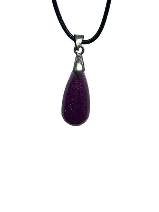 A small, elongated teardrop-shaped resin pendant in a rich plum purple with a fine glittery shimmer throughout. It hangs from a silver-toned bail on a black braided cord against a pale background.