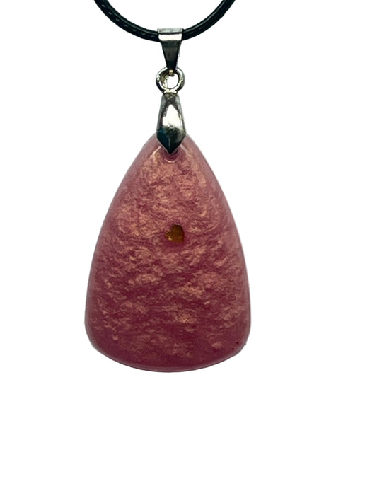 A rounded teardrop-shaped resin pendant in soft dusty rose pink with a velvety suede-like texture and warm coppery-gold tones throughout. It hangs from a silver-toned bail on a black braided cord against a pale background.
